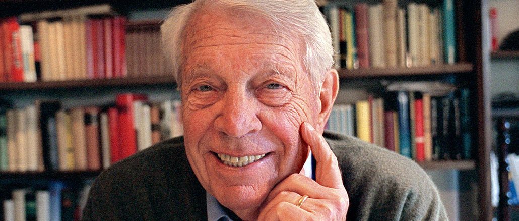 Herbert Reinecker, aufgenommen vor einer Bücherwand.