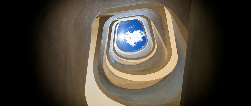 Blick von unten durch ein spiralförmiges, organisch geschwungenes Treppenhaus nach oben zum Himmel. In der Mitte ist ein rechteckiger Ausschnitt mit blauem Himmel und einer weissen Wolke sichtbar, durch den Sonnenlicht hereinfällt.