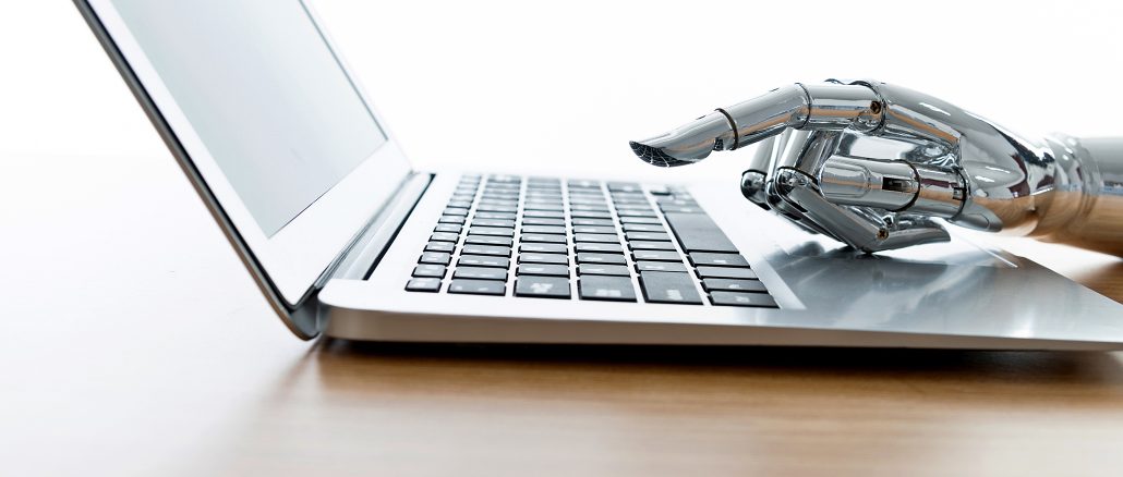 Detailaufnahme eines aufgeklappten Laptops auf einem Tisch; eine silberne, humanoide Roboterhand berührt die Tastatur, symbolisch für künstliche Intelligenz und automatisiertes Arbeiten am Computer.
